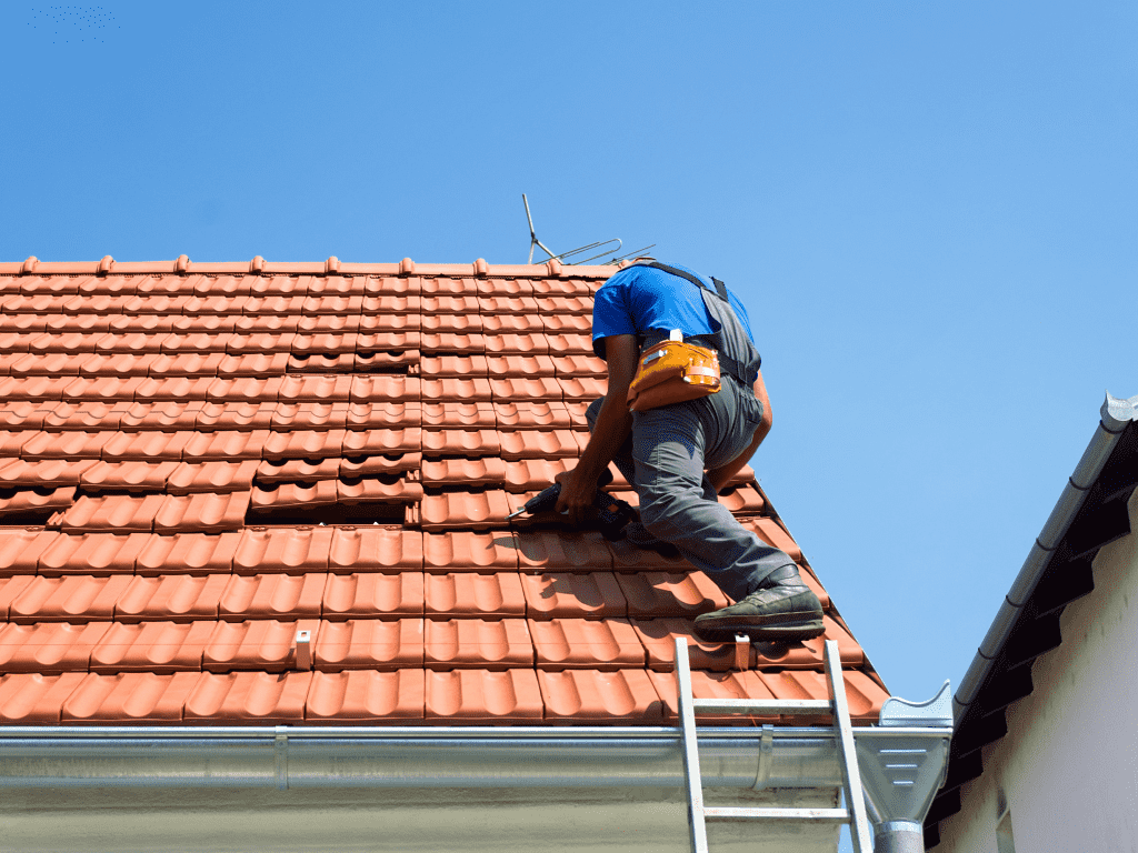 een man op een lader die aan het werk is op een dak met bruine dakpannen